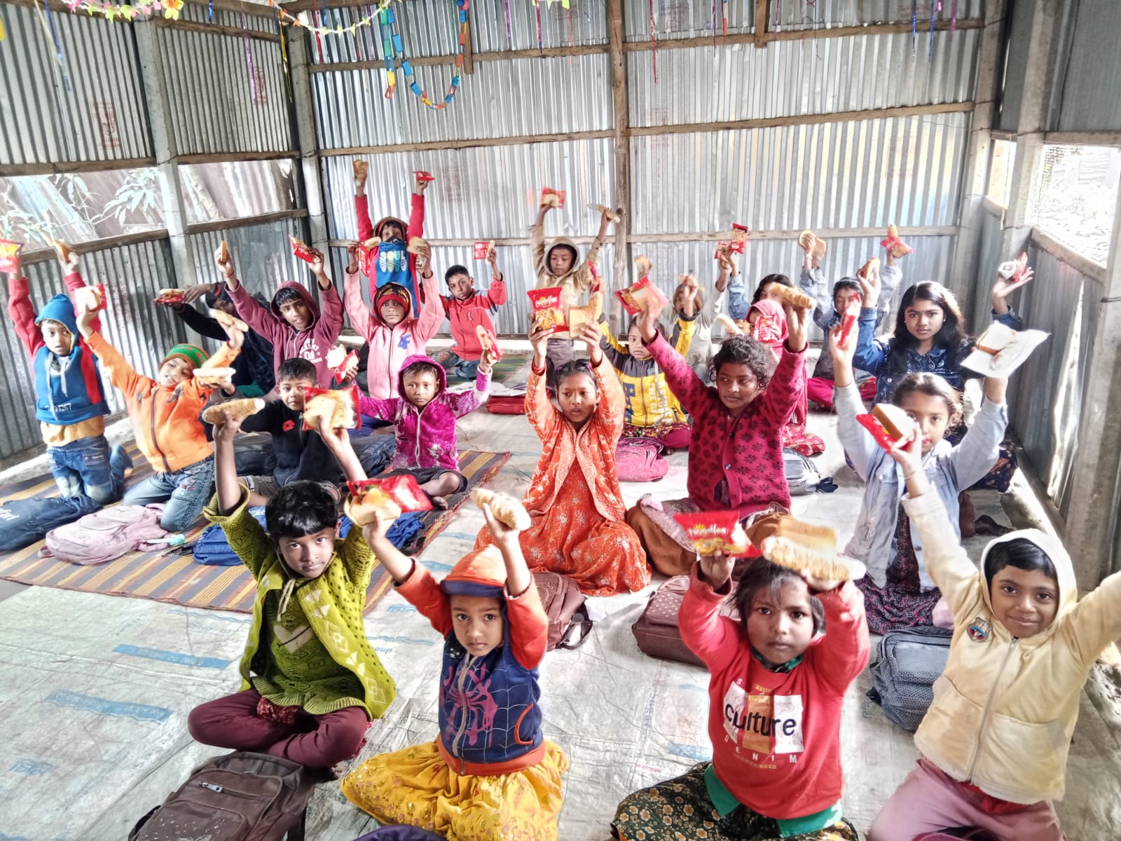 Children celebrating in a village classroom with hands raised